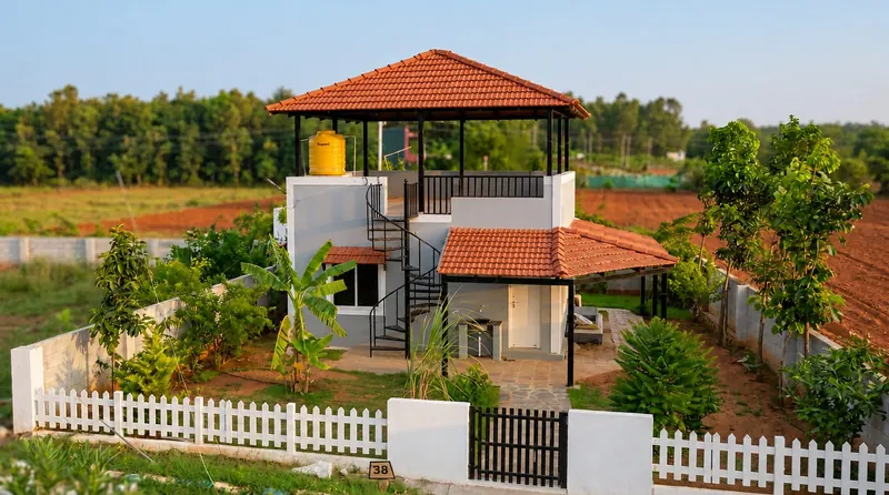 A real completed weekend villa at Stellar Mulberry with a rooftop gazebo seating deck, spiral staircase, white picket fence and a lush landscaped garden, photographed at golden hour
