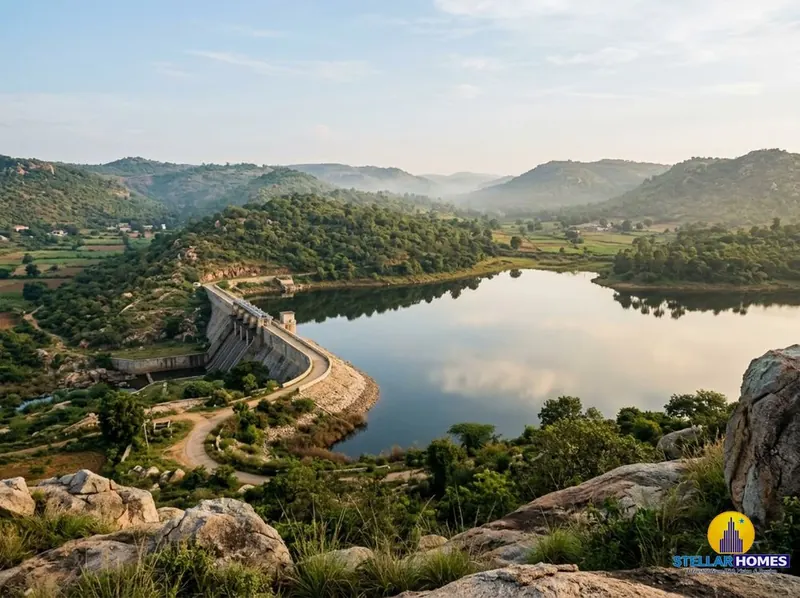 Jakkalamadagu Dam reservoir surrounded by rolling green hills under an open sky